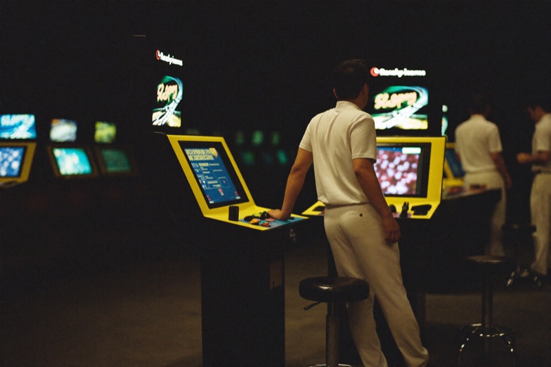 A player standing up from a slot stool and stepping away with one hand still on the cabinet, the screen lit behind him and the row quiet