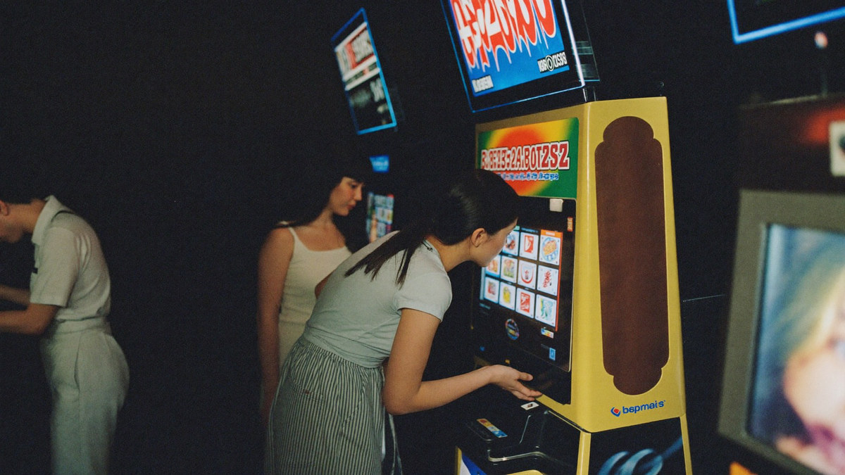 Two friends sharing one slot cabinet, one leaning in to press spin while the other watches the reels