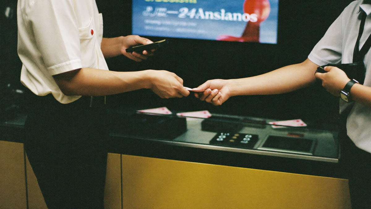 A cashier sliding notes under the counter glass to a player who is putting them into his wallet