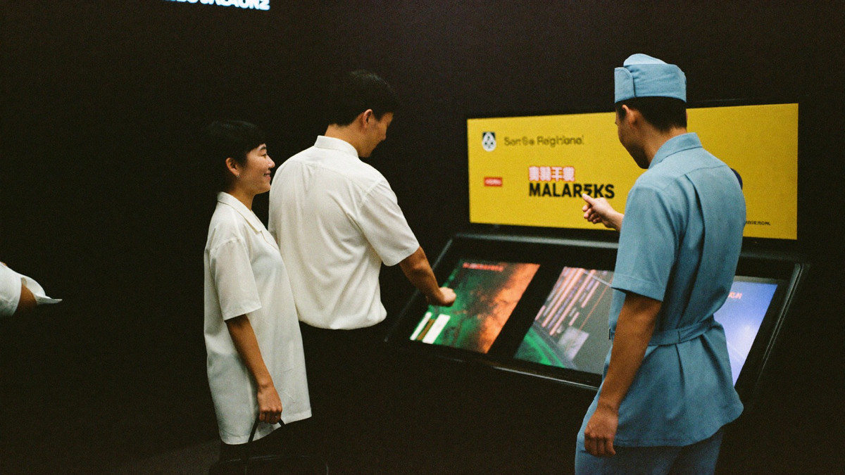 A couple arriving on the slot floor, the man pointing at a cabinet while a host gestures them towards it